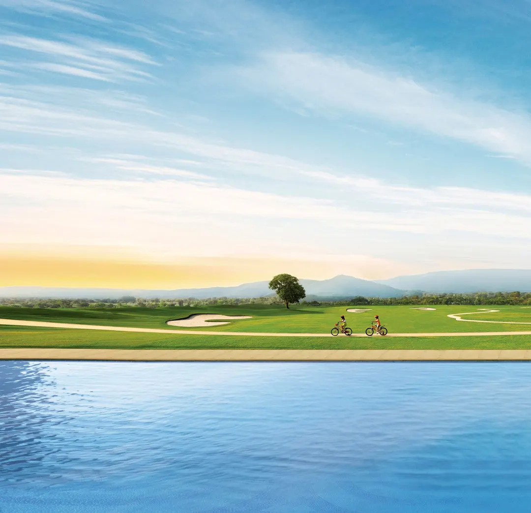 Children cycling along a golf course beside an infinity pool at sunrise