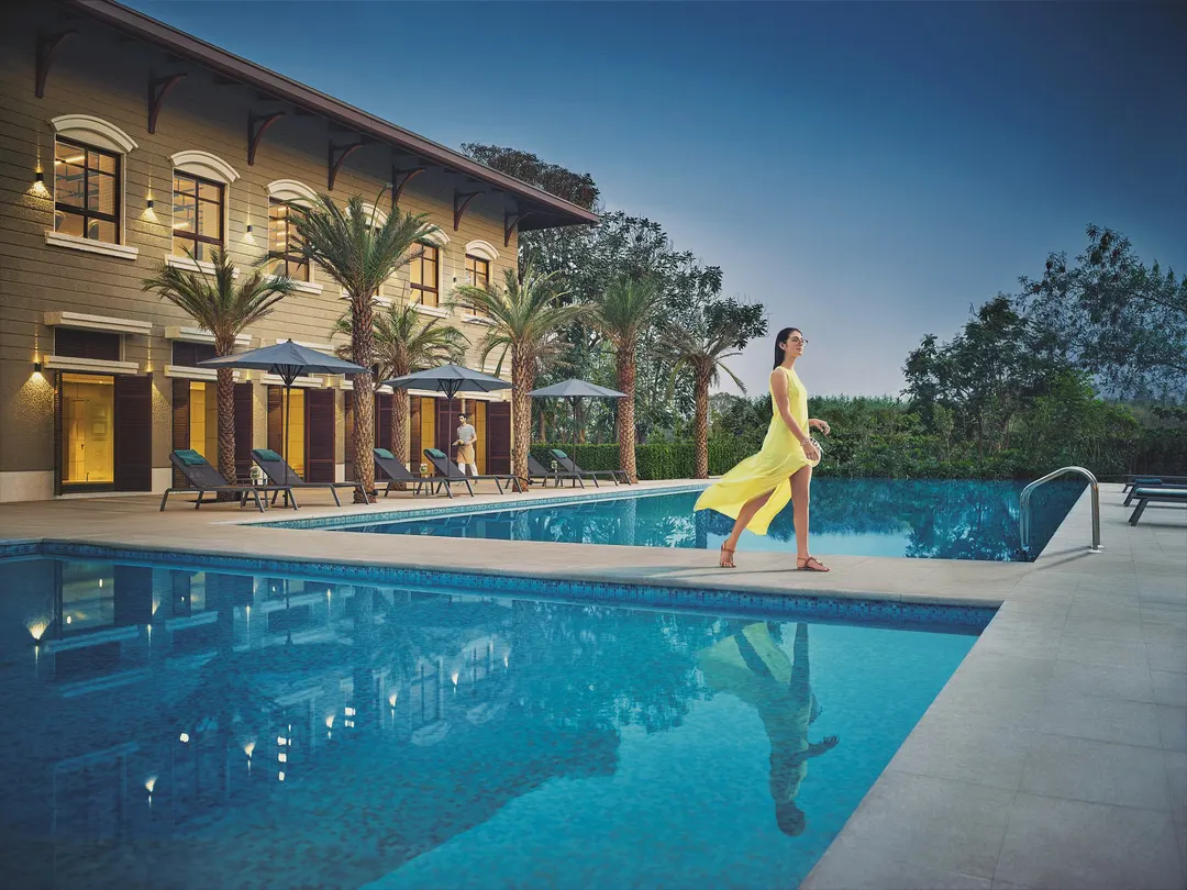 A resident strolling beside a clubhouse pool at dusk